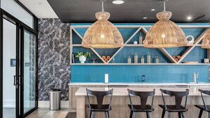 Une cuisine moderne avec un mur de crédence bleu, un mur décoré d’un motif noir et blanc, et trois suspensions lumineuses.