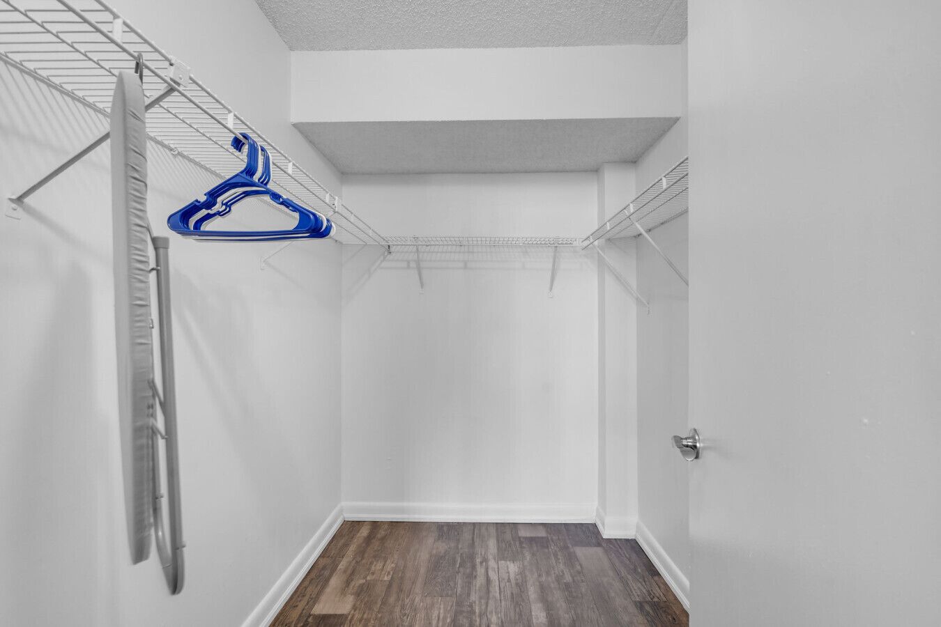 A walk-in closet with a metal shelving unit, a hanging rack, and a door.