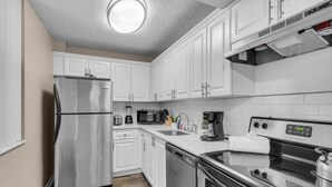 Una cocina moderna con armarios blancos, electrodomésticos de acero inoxidable, horno integrado y microondas.