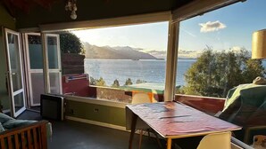 A room with a view of the sea, a table, a chair, and a small seating area. - Loft with incredible lake views (San Carlos de Bariloche)