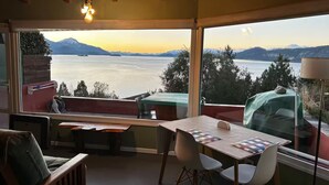 Een gezellige kamer met uitzicht op een meer en bergen, met een tafel met stoelen, een bank en een hanglamp.