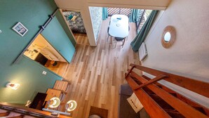 A room with a wooden floor, a white table with chairs, and a view of the outside through a window.