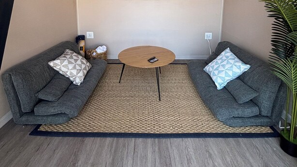 A cozy seating area with two grey sofas, a small round table, and a ceiling-mounted projector.