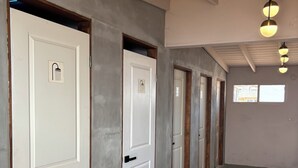 A hallway with white doors, each marked with a shower symbol, leading to individual rooms.