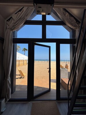 Une pièce dotée d’une grande porte-fenêtre coulissante donnant sur une plage.