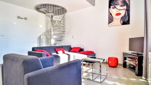 A modern living room with a spiral staircase, a sofa set, a coffee table, and a flat-screen TV. - Beautiful apartment in Uzès with WiFi (Uzès)