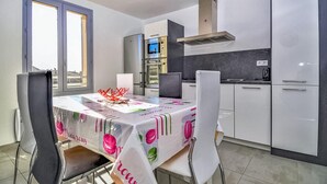 A modern kitchen with stainless steel appliances, a dining area with a table covered in a colorful tablecloth, and a view through the window. - Beautiful apartment in Uzès with WiFi (Uzès)
