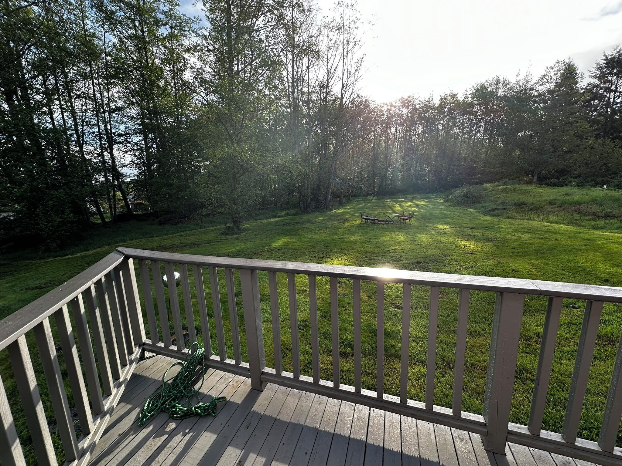 A deck with a view of a grassy area and trees.