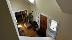 Une pièce de style « loft » avec un plafond en pente, un plancher en bois, une grande fenêtre et une vue sur l’extérieur.