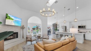 Een moderne woonkamer met een open haard, een bank en een televisie waarop een strand te zien is.