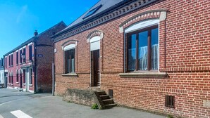 Ein rot backsteiner Gebäude im traditionellen Stil, mit einer Treppe, die zu einer Tür führt, und blauem Himmel im Hintergrund.