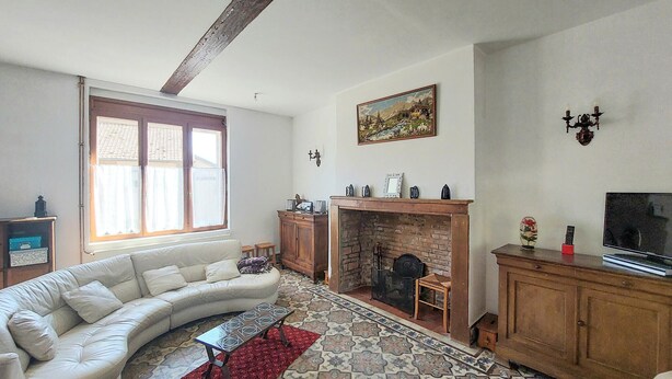 Ein Wohnzimmer mit einem gebogenen weißen Sofa, einem Kamin, einem Fernseher und einem Fliesenboden.