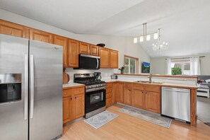 A modern kitchen with wooden cabinets, stainless steel appliances, a built-in oven, and a dishwasher.