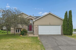 Une maison à deux étages avec un garage, une entrée en briques et une pelouse bien entretenue.