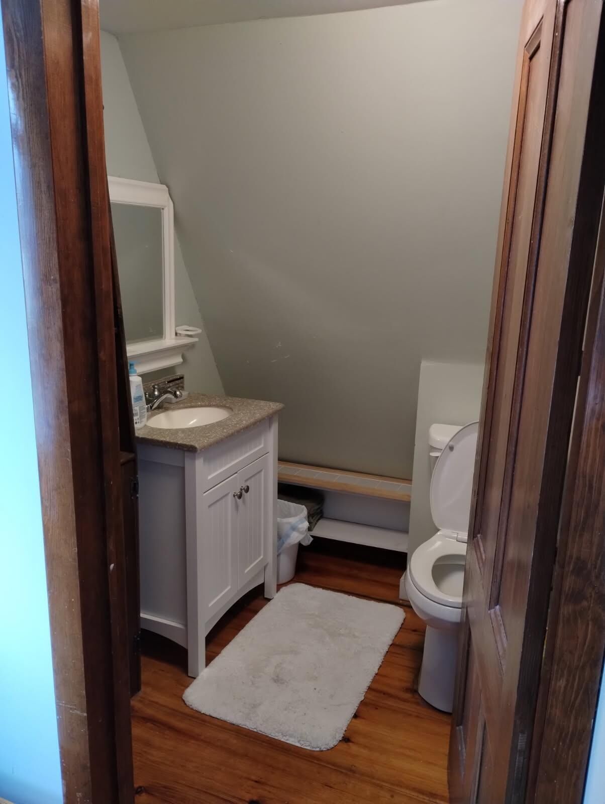 Un baño pequeño con un lavamanos, tocador y retrete blancos.