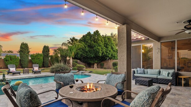 Eine Terrasse mit Feuerstelle, Gartenmöbeln und einem Schwimmbad.