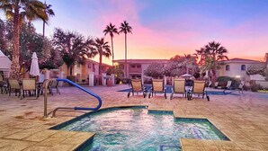 Zona de piscina con sillas de descanso y una palmera.