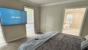 Une chambre à coucher avec un lit, un téléviseur fixé au mur et une vue sur l’extérieur.
