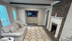 Un salon moderne avec une grande télévision, une cheminée et un tapis à motifs.