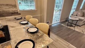 Un coin repas avec une table en marbre, des chaises et de l’argenterie disposée pour le repas.
