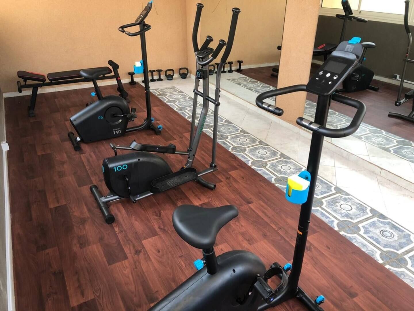 Ein Heimfitnessraum mit verschiedenen Trainingsgeräten, darunter ein Crosstrainer, ein Ergometer und ein Laufband.