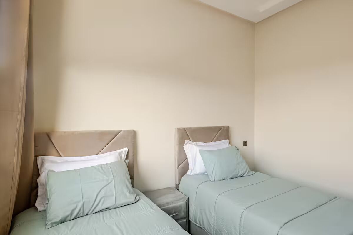 Une chambre avec deux lits, chacun doté d’une tête de lit et d’une table de chevet.