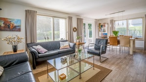 Una sala moderna con un sofá, una mesa de centro de vidrio y un comedor con sillas y una mesa.