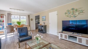 Una sala de estar moderna con un televisor de pantalla plana, una mesa de centro de vidrio y un área de estar acogedora.