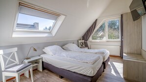Un dormitorio con dos camas, un escritorio, una silla y un televisor.