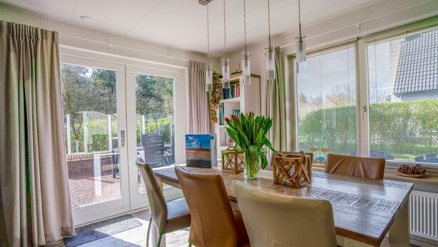 Un comedor con una mesa de madera, sillas color beige y una planta en maceta.