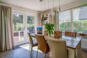 A dining area with a wooden table, beige chairs, and a potted plant. - Charming Villa Near the sea and Forest With Sauna (De Koog)