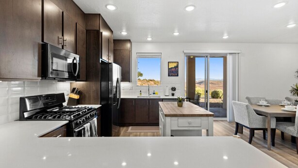 A modern kitchen with dark wood cabinets, stainless steel appliances, and a large island.