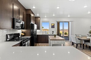 Une cuisine moderne avec des meubles en bois foncé, des appareils électroménagers en acier inoxydable et un grand îlot central.