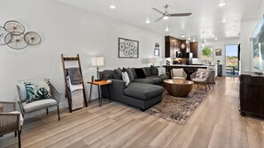 A modern living room with a grey sectional sofa, a wooden coffee table, and a patterned rug.