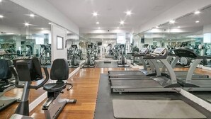 A gym with cardio equipment, weight machines, and mirrors on the walls.