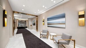 A modern hotel lobby with a marble floor, a black carpeted path, and contemporary furniture.