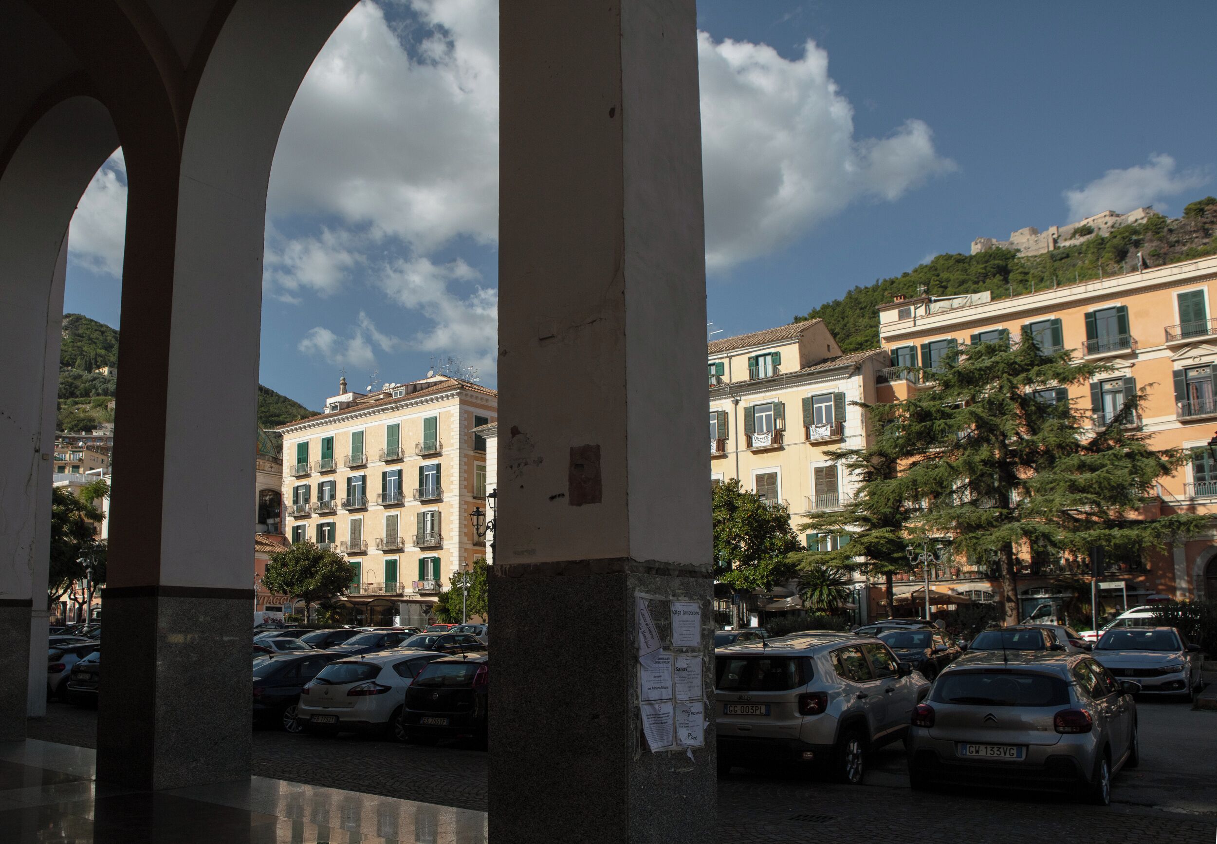 Un espace de stationnement avec plusieurs voitures, un immeuble doté de balcons et un ciel dégagé.
