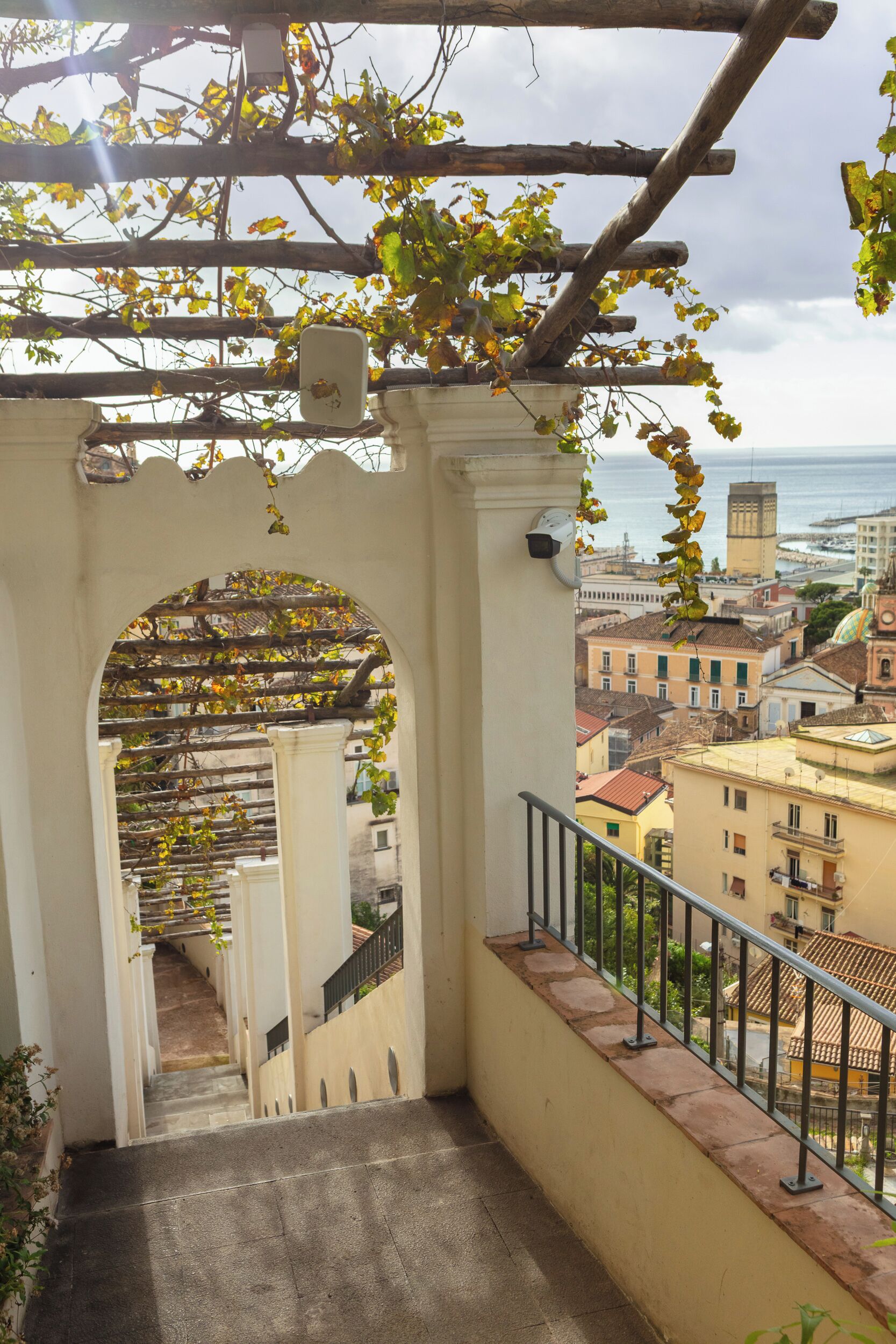A staircase leading to a balcony with a view of the cityscape and the sea.