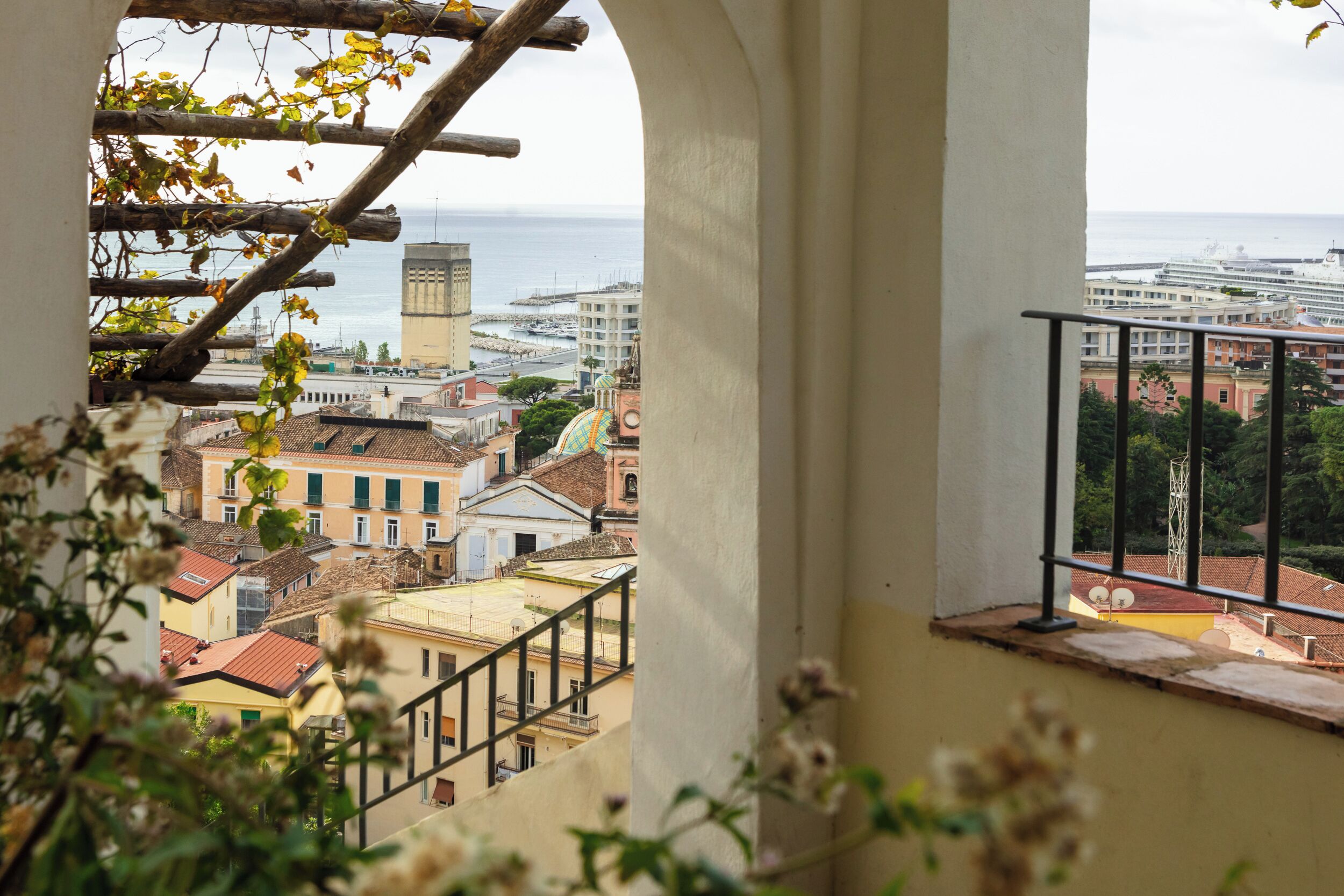 A view from a balcony overlooking a coastal cityscape with buildings and a marina.