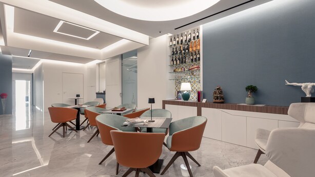 A modern dining area with a marble floor, orange chairs, and a glass-top table. - ViaRomaHome (Salerno)