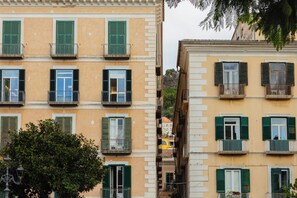 A row of buildings with multiple windows and balconies, some with shutters. - ViaRomaHome (Salerno)