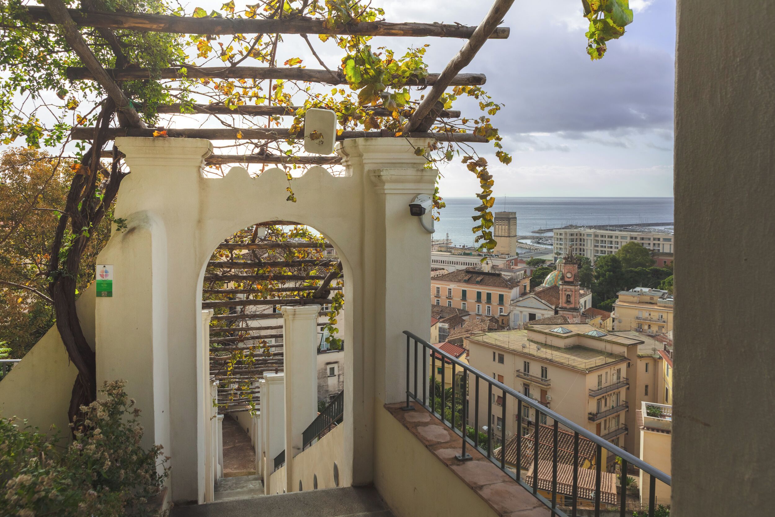 A staircase with a view of the sea and buildings in the distance.