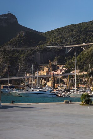 A marina with boats docked, a bridge in the background, and buildings on a hillside. - ViaRomaHome (Salerno)