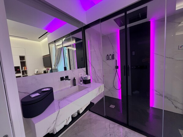 A modern bathroom with a large mirror, a vanity with a black sink, and a glass-enclosed shower area. - ViaRomaHome (Salerno)