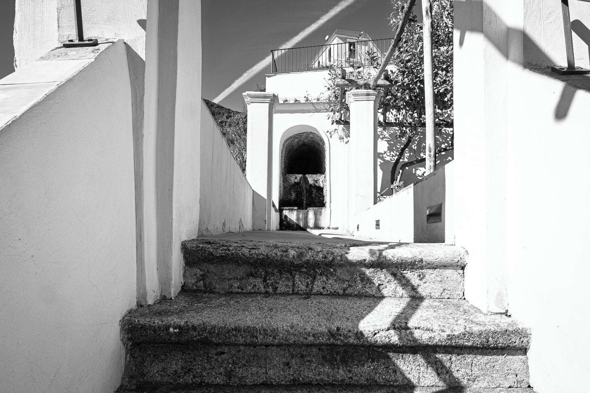 Un escalier menant à l’entrée d’un immeuble, avec un balcon.