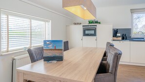 Een moderne keuken met witte kastjes, een inbouwoven en een koffiezetapparaat.