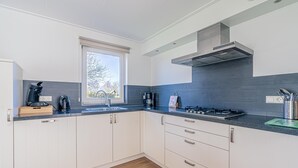 Een moderne keuken met witte kastjes, een zwart aanrechtblad en een raam dat natuurlijk licht binnenlaat.