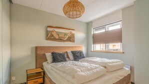 Une chambre à coucher comprenant un lit, une table de chevet et une œuvre d’art accrochée au mur.