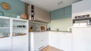 Une cuisine moderne avec des meubles blancs, un plan de travail en bois et un four encastré.