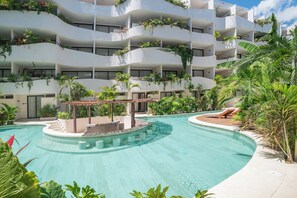 Ein modernes Hotel mit einem zentral gelegenen Pool, mehreren Balkonen mit Bepflanzung und einer Sonnenterrasse.